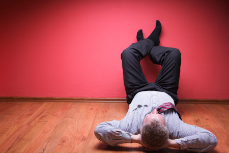 men lying in the floor on red wall backgroundの写真素材