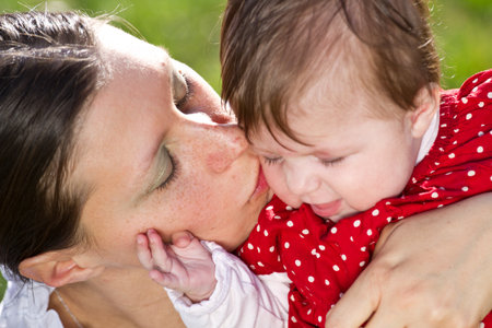 mother kissing baby in the parkの写真素材