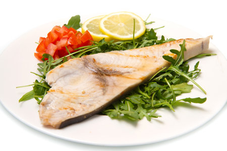 roasted swordfish with lemon, salad and tomatoes on white dish の写真素材