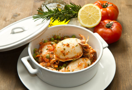 a white bowl with cuttlefish with peas and fresh tomatoes, lemon and oilの写真素材