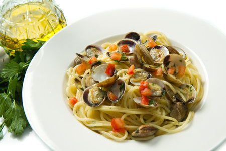white dish of spaghetti,clams , tomatoes, oil and parsleyの写真素材