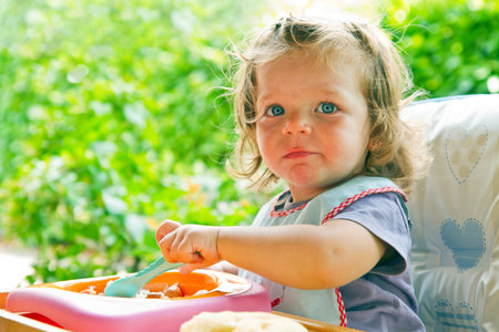 the baby girl eating with spoon の写真素材