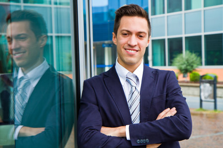 Smiling young businessman standing outside a building の写真素材