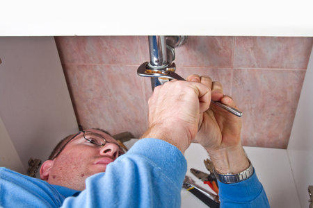a plumber repairing a broken sink in bathroom の写真素材