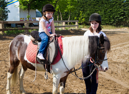 little girl is riding a horse の写真素材