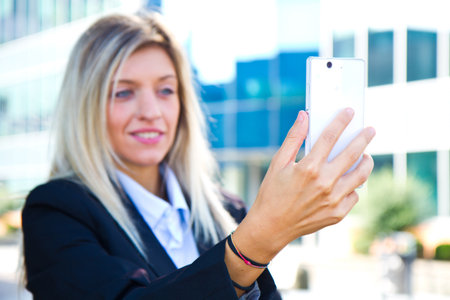 Beautiful business woman takes a selfie with her cell phoneの写真素材