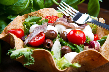 mixed salad with mozzarella and anchovy in a bread basketの写真素材