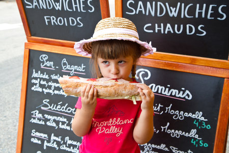 young girl eating a big sandwichの写真素材