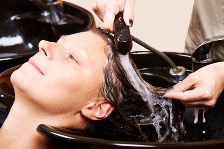 Hairdressers hand washing female customer's hair in salonの写真素材
