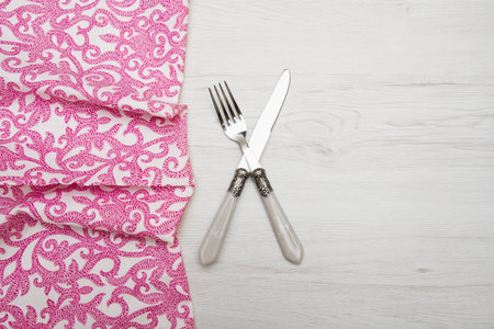 knife and fork at napkin on white wooden background