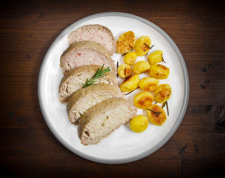 Meat loaf with roasted potatoes on dishの写真素材