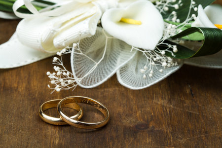 Wedding rings with calla bouquet on wooden backgroundの写真素材
