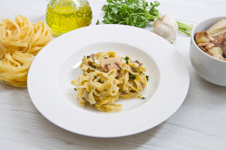 dish with tagliatelle and mushrooms and fresh ingredients on white woodの写真素材