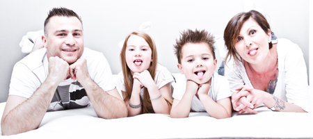 happy smiling young family with two children lying on mattressの写真素材
