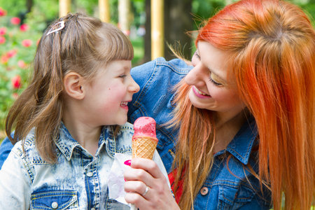 Beautiful woman and little girl eating a delicious ice cream. Girl relaxing in the parkの写真素材