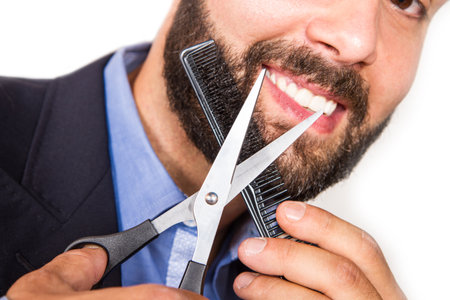 Portrait of a man grooming his beard with scissorsの写真素材