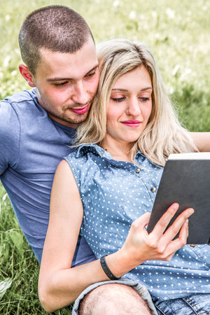 engaged couple at the park while reading a book in relaxの写真素材