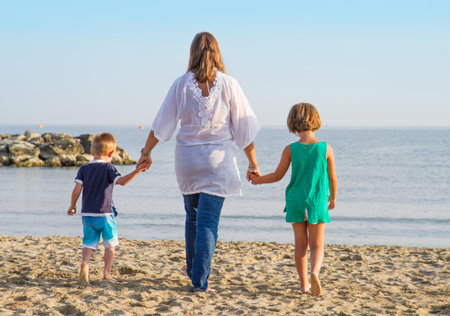 Mom and daughter walk hand in hand at the beachの写真素材