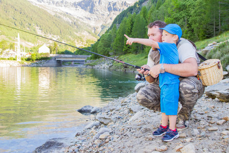 father and son fishing in a mountain lakeの写真素材
