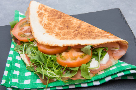 typical piadina romagnola with ham, cheese and rocketの写真素材