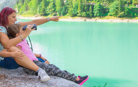 mom and daughter look at something with binoculars during an excursion to the lakeの写真素材