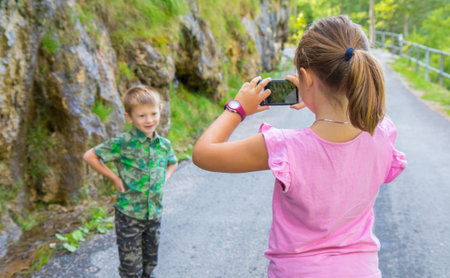 little girl takes a picture of her little brotherの写真素材