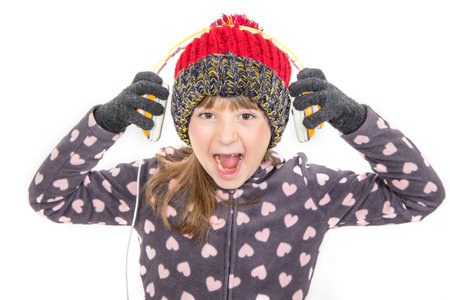 young girl with gloves and woolen hat is listening music with headphone