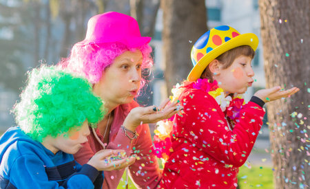 a mother and her children are playing with confetti in carnival costumeの写真素材