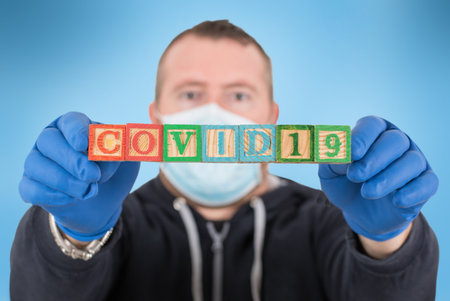 The epidemic of the covid-19 virus. man with wooden cubes letter with the COVID 19 writtenの写真素材