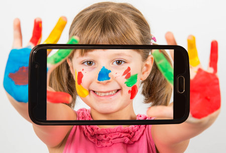 smiling little girl with hands painted in colorful paintsの写真素材