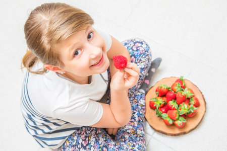 happy child is eating fresh strawberryの写真素材