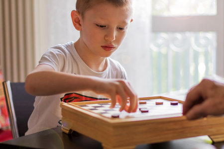 young child plays chess with his grandfatherの写真素材