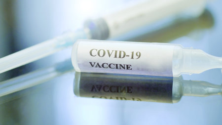 Close-up of medical worker hand with blue surgical gloves looking holding a vial of coronavirus vaccineの写真素材