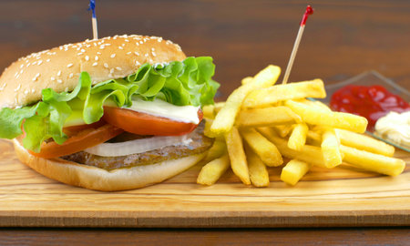 Delicious grilled hamburger with potato chips on wooden boardの写真素材