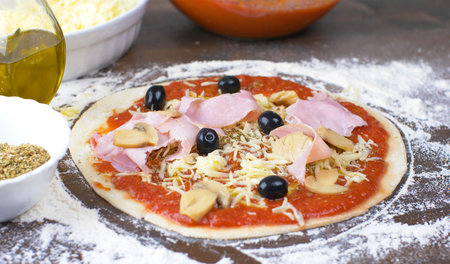 pizza dough with ham, oregano, mushroom, olive. Italian traditional recipe of pizza.の写真素材