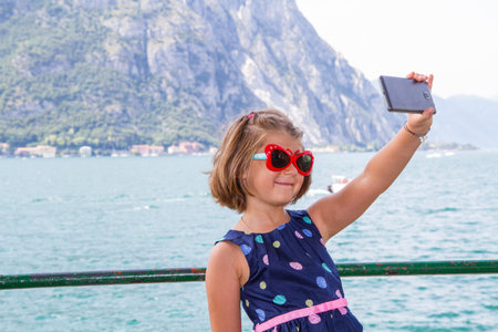 smiling young girl is taking a selfie near the lakeの写真素材