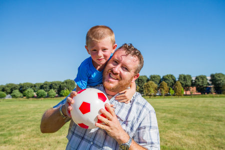 father and son playing with soccer ballの写真素材