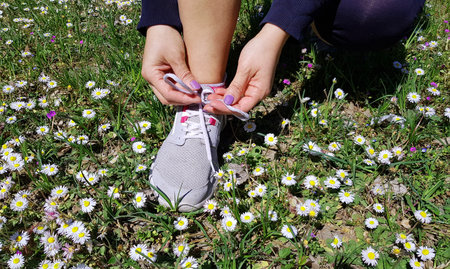 Young athlete woman tying running shoes in the park outdoorの写真素材
