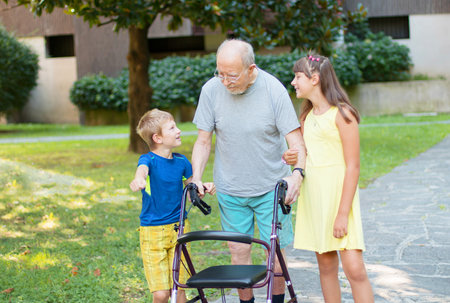 grandchildren accompanies their grandfather to walk helping himの写真素材