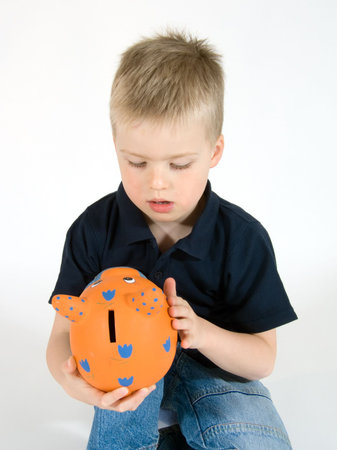 young boy stroking his orange piggy bankの写真素材