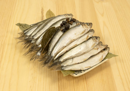 small Baltic fish - spicy salted sprats stands on a pine table