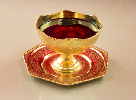 Ancient golden chalice with red wine on a marble table. blood of Christの写真素材