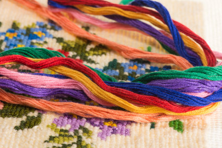 skeins of multicolored threads for embroidery - muline. against the background of cross-stitch