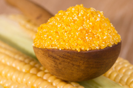 corn grits in old wooden spoon and cobs