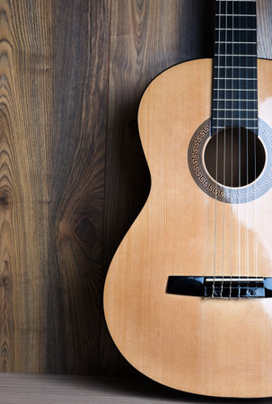 acoustic six-string guitar on the background of wooden panels