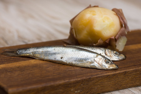 spicy salted anchovies and boiled potatoes on a wooden boardの写真素材