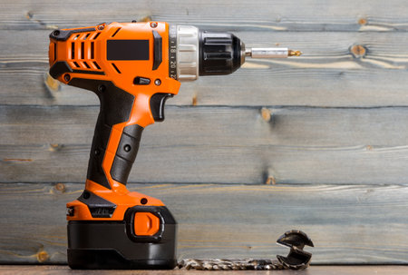 battery powered drill and drill on a wooden surface