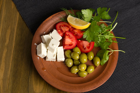 feta cheese, tomatoes, olives and herbs in a clay plate - Greek lunchの写真素材