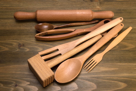 A set of wooden kitchen utensils on a dark board