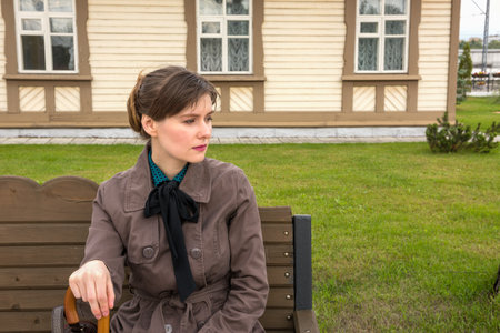 Portrait of a young woman sitting on a bench. Waiting for the train at the station.の写真素材